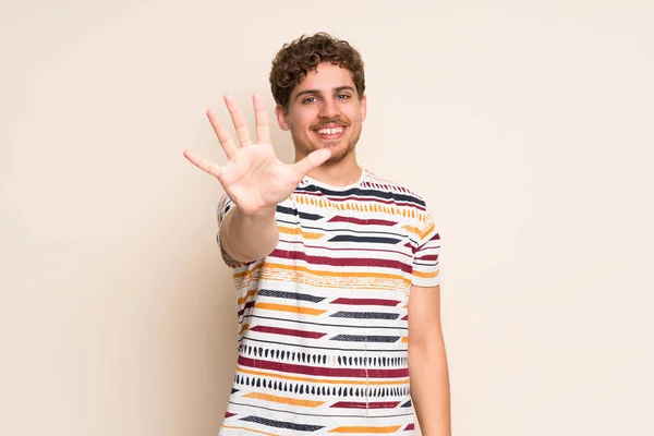 Blonder Mann Über Isolierte Mauer Der Mit Fingern Fünf Zählt — Stockfoto