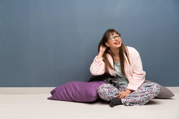 Woman in pajamas on the floor thinking an idea while scratching head