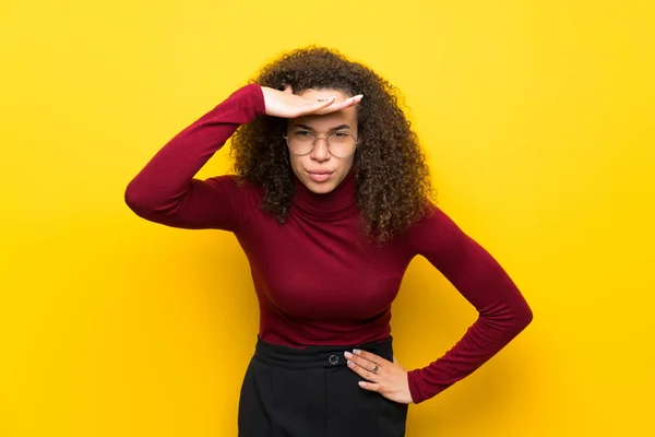 Dominican woman with turtleneck sweater looking far away with hand to look something