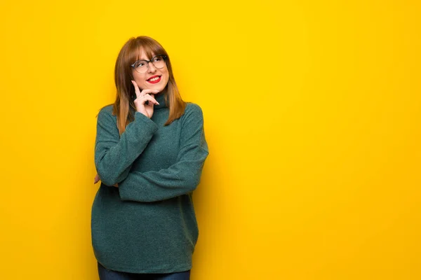 Kobieta Okularach Żółty Ścianę Myślenie Pomysł Sprawdzając Jednocześnie — Zdjęcie stockowe