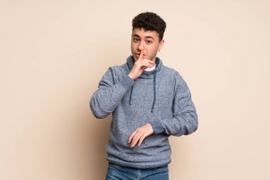Genç adam bir işaret parmağını ağzına koyarak sessizlik jest gösteren izole duvarın üzerinden