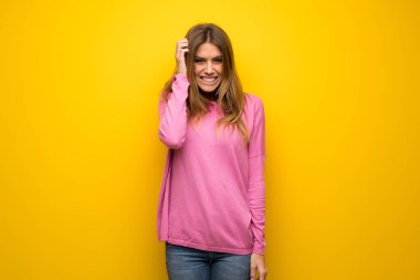 Kadın sarı duvarın şüpheleri üzerinden pembe kazak