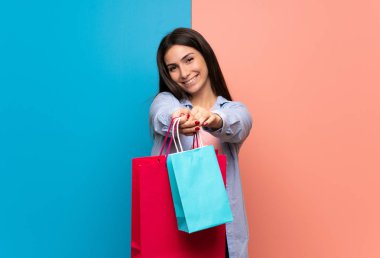 Pembe ve mavi duvar alışveriş torbaları bir sürü tutan genç kadın