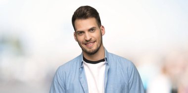 Açık havada önüne bakarak gülen yakışıklı adam