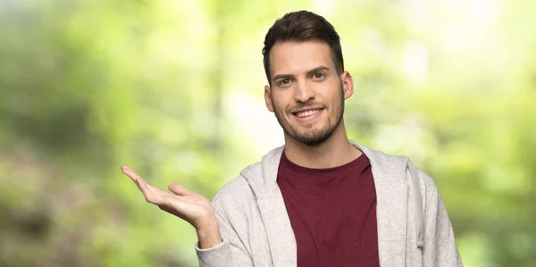 Man Sweatshirt Holding Copyspace Imaginary Palm Insert Park — Stock Photo, Image