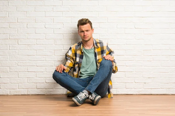 Blonde Man Zittend Vloer Met Droevige Depressief Expressie — Stockfoto