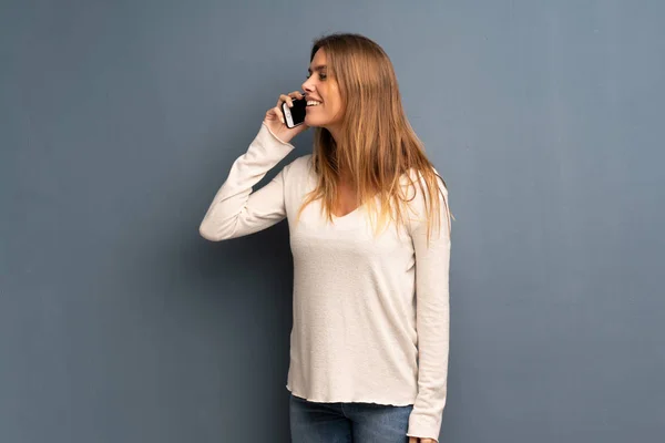 Блондинка Сером Фоне Поддерживает Разговор Мобильным Телефоном — стоковое фото