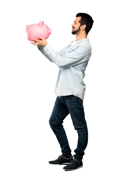 Hombre guapo con barba sosteniendo una alcancía — Foto de Stock