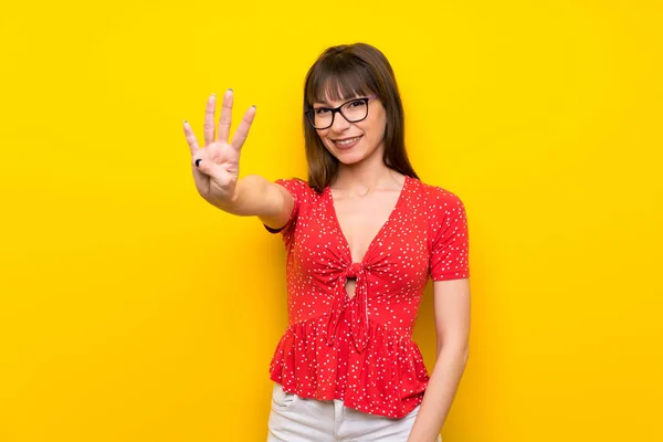 Young woman over yellow wall happy and counting four with fingers