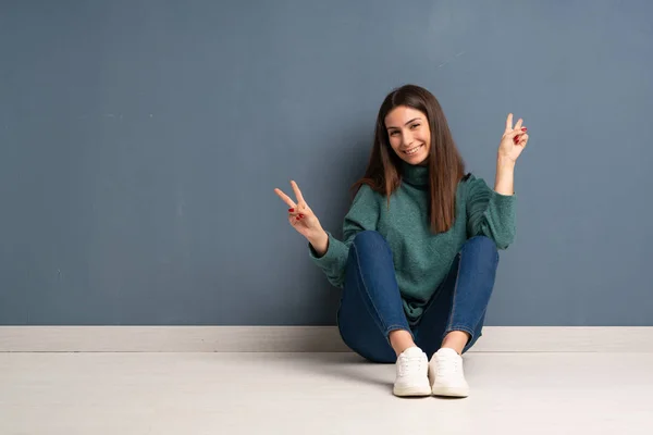 Jonge Vrouw Zittend Vloer Glimlachend Overwinning Teken Met Beide Handen — Stockfoto