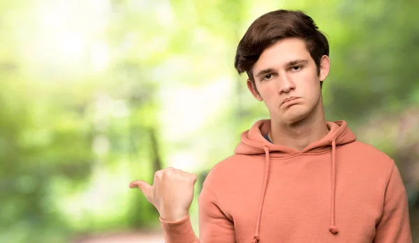 Adolescente Hombre Con Sudadera Infeliz Apuntando Lado Aire Libre —  Fotos de Stock