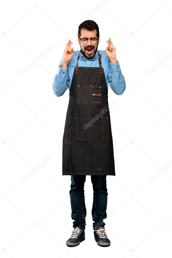 Full-length shot of Man with apron with fingers crossing over isolated white background