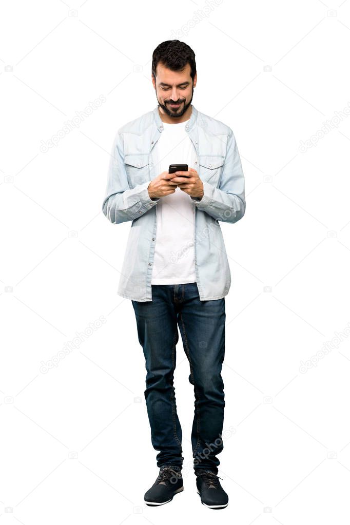 Full-length shot of Handsome man with beard sending a message with the mobile over isolated white background