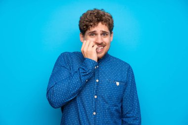 Gergin ve korkmuş izole mavi duvarın üzerinden sarışın adam