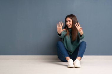 Yerde oturan genç kadın parmaklarıyla sekizi sayıyor.