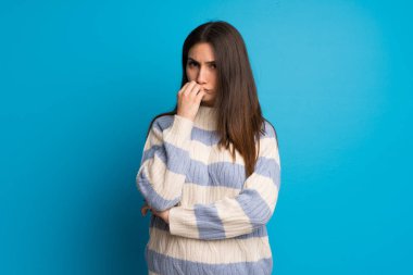 Genç kadın mavi duvarın şüpheleri üzerinden