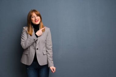 Kızıl saçlı bir iş kadını tarafına işaret eden bir ürün sunmak