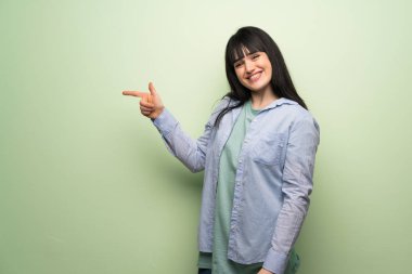 Yeşil duvar işaret parmağı lateral pozisyonda Side'ye genç kadın