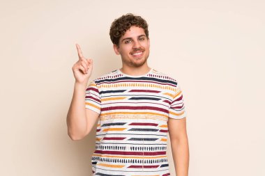 Sarışın adam gösteren ve en iyi iz içinde parmak kaldırma izole duvarın üzerinden