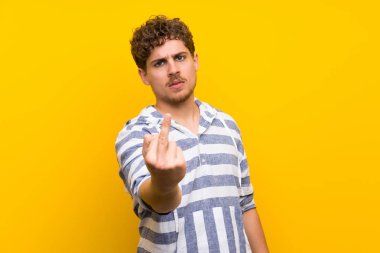 Sarışın adam sarı duvar boynuz jest yapma