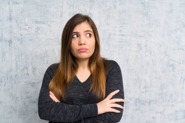 Genç kız ayakta ve bir fikir düşünmek grunge duvarın üzerinden