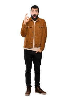 Sakal şaşırmış ve izole beyaz arka plan üzerinde gösteren ok işareti ile yakışıklı adam