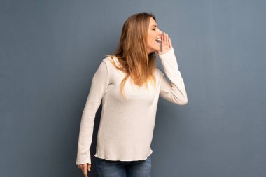 Lateral için açık ağızlı bağırmayı gri arka plan üzerinde sarışın kadın