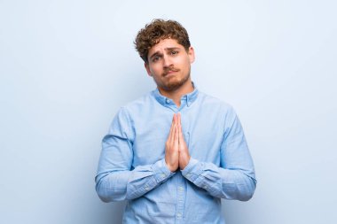 Sarışın adam mavi duvarın üzerinden birlikte palm tutar. Kişi için bir şey sorar