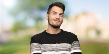 Yakışıklı adam açık havada gülümseyerek bakan