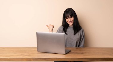 Ürün sunmak için tarafına işaret onu laptop ile çalışan genç kadın
