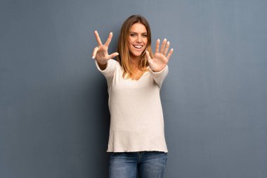 Sekiz parmak ile sayma gri arka plan üzerinde sarışın kadın