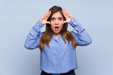 Sürpriz ifade ile izole mavi duvarın üzerinden genç kız