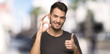 Siyah gömlek gösteren ok işareti ile ve açık havada jest bir başparmak veren adam