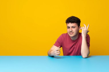 Renkli duvar ve masa şüpheniz sahip genç adam