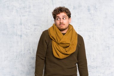 Sarışın adam yan seyir şüpheler jest yapma grunge duvarın üzerinden