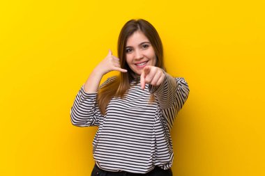 Telefon jest yapma ve açık işaret sarı duvarın üzerinden genç kız