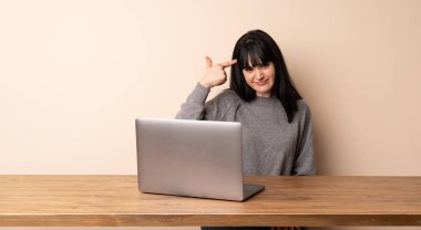 Parmak kafasına koyarak delilik jesti yapmak onu laptop ile çalışan genç kadın