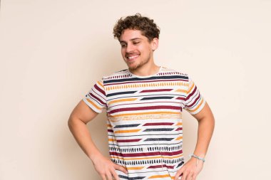 Sarışın adam silah, kalça ile poz ve gülümseyen izole duvarın üzerinden