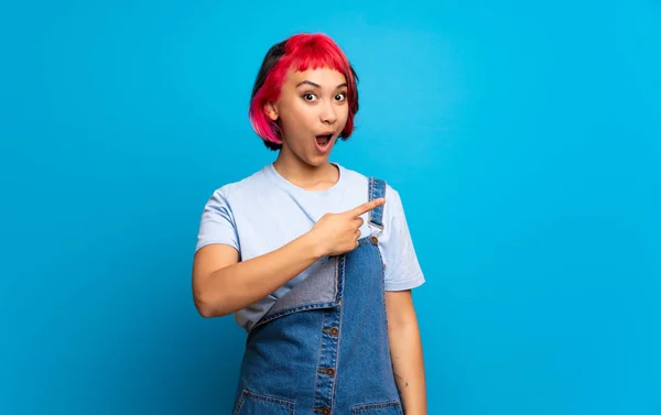 Mujer Joven Con Pelo Rosa Sobre Pared Azul Sorprendido Apuntando — Foto de Stock