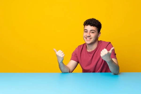 Jovem Com Parede Colorida Mesa Com Polegares Para Cima Gesto — Fotografia de Stock