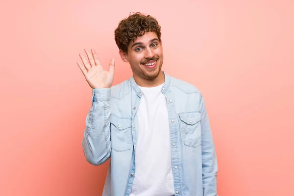 Blonder Mann Grüßt Mit Fröhlichem Gesichtsausdruck Über Rosa Wand — Stockfoto