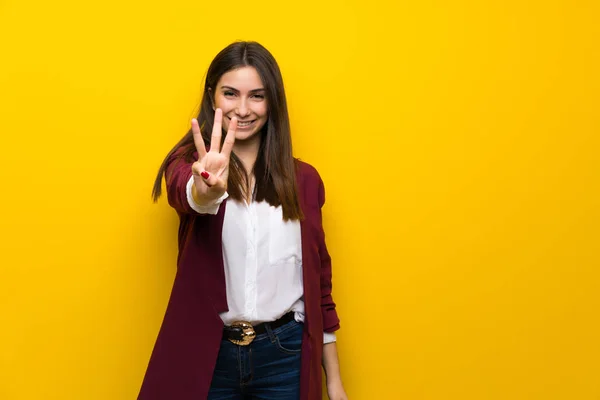 Młoda Kobieta Żółty Ścianę Trzy Szczęśliwe Liczenia Palcami — Zdjęcie stockowe