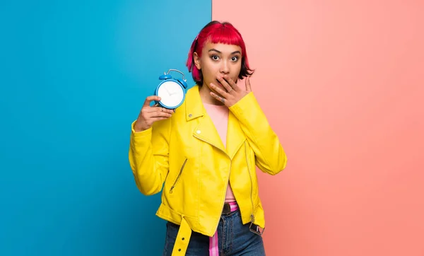 Young woman with yellow jacket holding vintage alarm clock