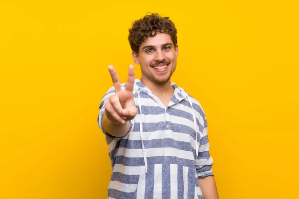 Hombre Rubio Sobre Pared Amarilla Sonriendo Mostrando Signo Victoria —  Fotos de Stock