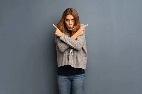 Mujer Rubia Sobre Fondo Gris Apuntando Los Laterales Teniendo Dudas — Foto de Stock