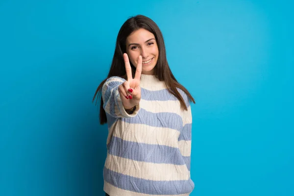 Mujer Joven Sobre Pared Azul Sonriendo Mostrando Signo Victoria —  Fotos de Stock