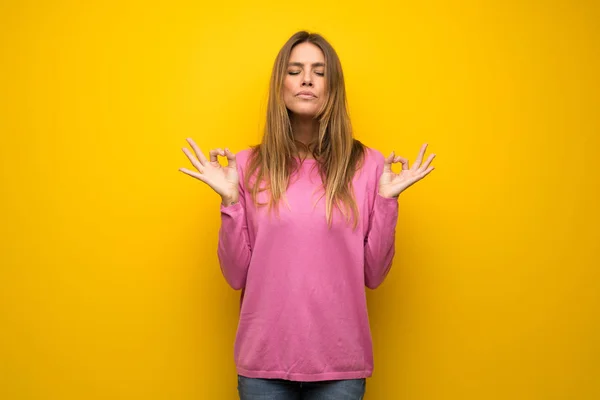 禅では黄色の壁にピンクのセーターの女性をもたらす — ストック写真