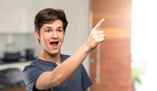 Teenager man pointing away at indoors