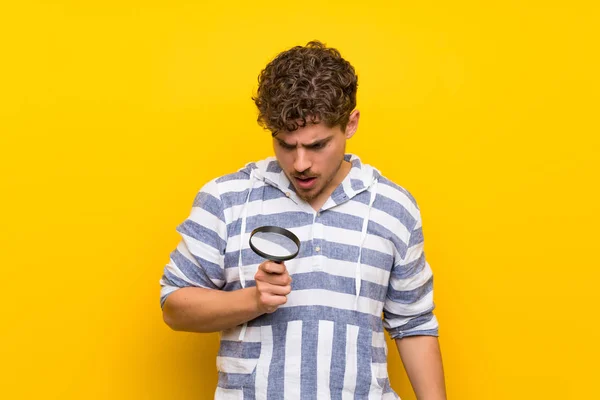 Homem Loiro Sobre Parede Amarela Segurando Uma Lupa — Fotografia de Stock