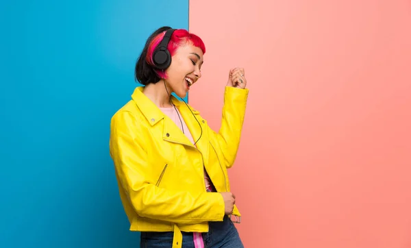 Young woman with yellow jacket listening to music with headphones